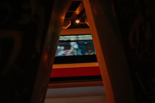 A blurred view of a train passing by, framed by a narrow, dark opening with dim lighting