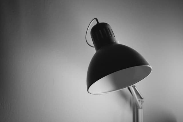 A black and white photograph of a desk lamp casting a shadow on a wall