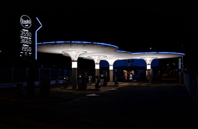 A gas station at night with illuminated signage and canopy, featuring blue and white lights