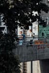 Two people walking on a graffiti-covered bridge, partially obscured by tree leaves
